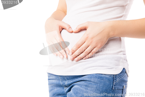 Image of Close-up of pregnant woman embracing belly with heart shape