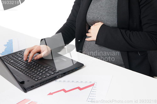 Image of Businesswoman waiting for baby while working on laptop