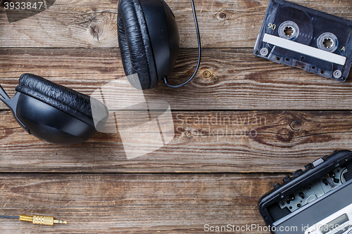 Image of Cassette tapes, cassette player and headphones over wooden table. top view.