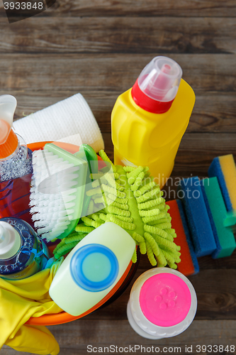 Image of Plastic bucket with cleaning supplies on wood background