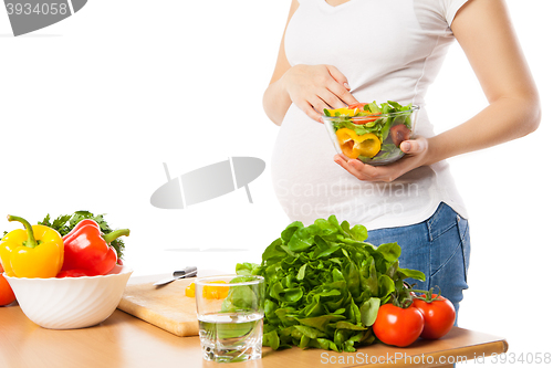 Image of Close-up of pregnant woman holding bowl with fresh vegetables