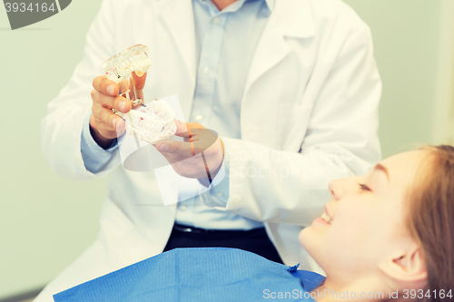 Image of close up of dentist showing teeth maquette to girl