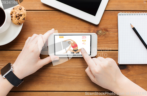 Image of close up of woman with smartphone on wooden table