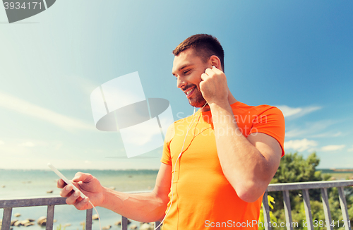 Image of smiling young man with smartphone and earphones