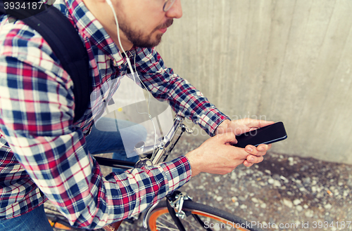 Image of hipster man in earphones with smartphone and bike