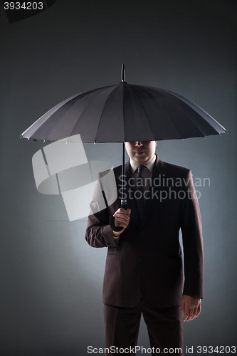 Image of Businessman under umbrella