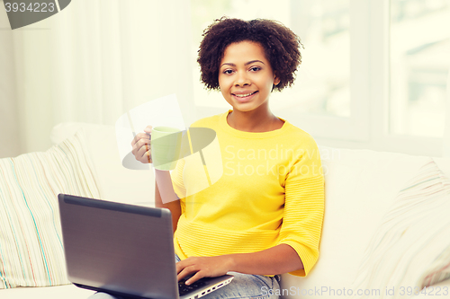 Image of happy african american woman with laptop at home