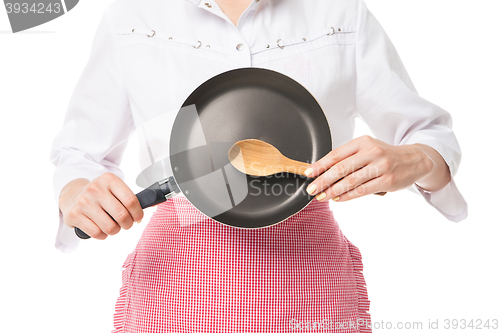 Image of Close-up of woman holding frying pan and wooden spoon