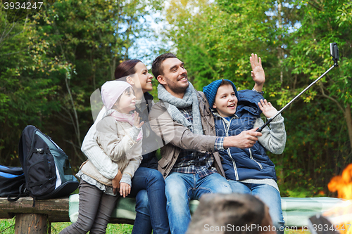 Image of family with smartphone taking selfie near campfire