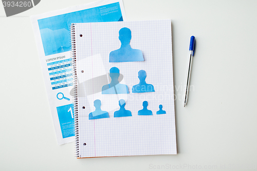 Image of close up of paper human shapes on notebook