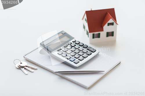 Image of close up of home model, calculator and notebook