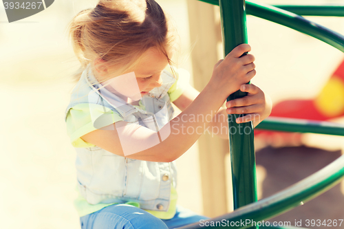 Image of happy little girl climbing on children playground