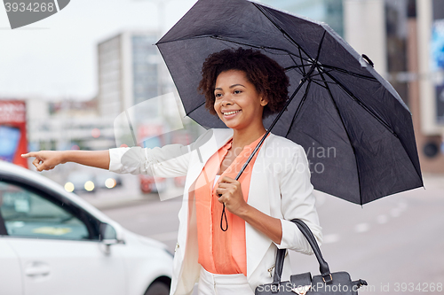 Image of happy african woman with umbrella catching taxi