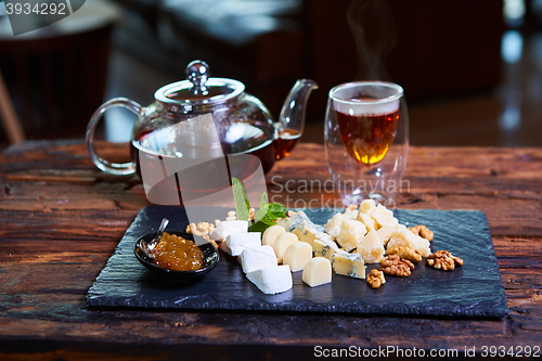 Image of various cheeses and tea on a wooden background