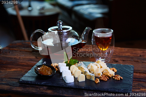 Image of various cheeses and tea on a wooden background