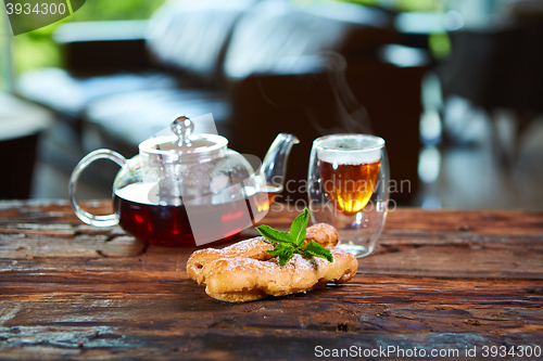 Image of Tasty eclair and cup of tea on wooden table