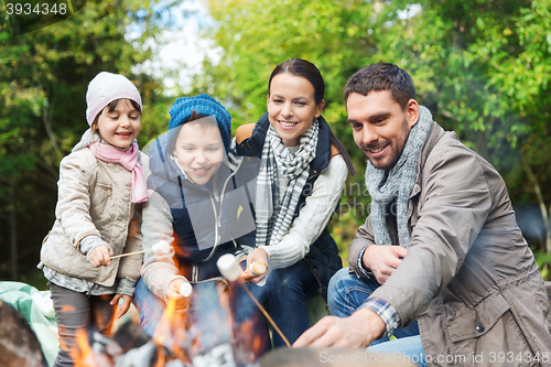 Image of happy family roasting marshmallow over campfire