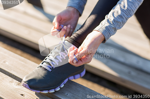 Image of close up of sporty woman tying shoelaces outdoors