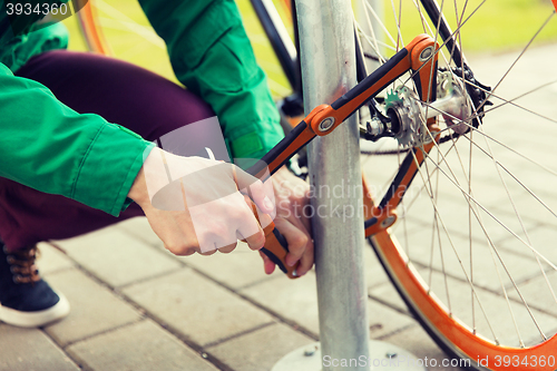 Image of close up of man fastening bicycle lock on parking