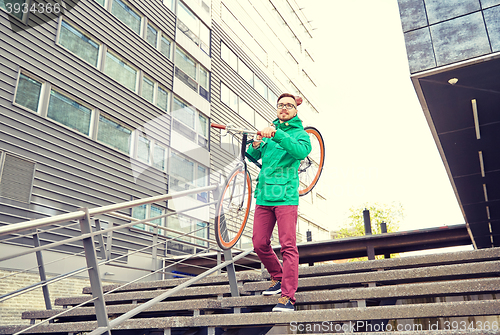 Image of young hipster man carrying fixed gear bike in city