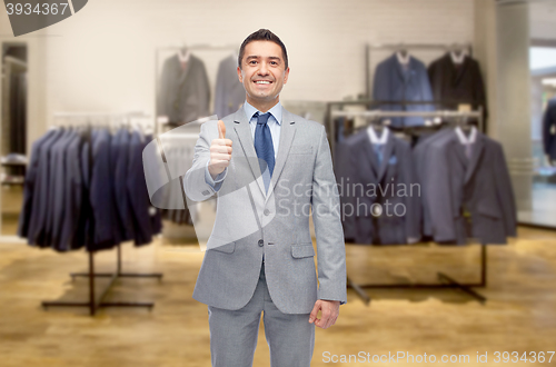 Image of happy businessman in suit over clothing store