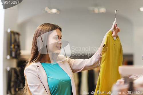 Image of happy young woman choosing clothes in mall