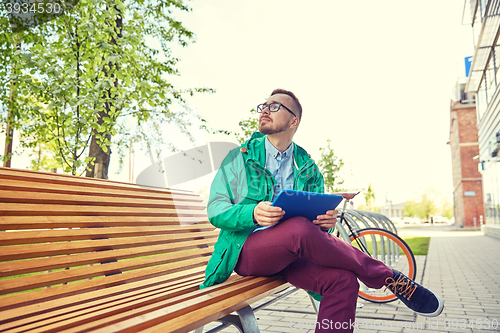 Image of happy young hipster man with tablet pc and bike