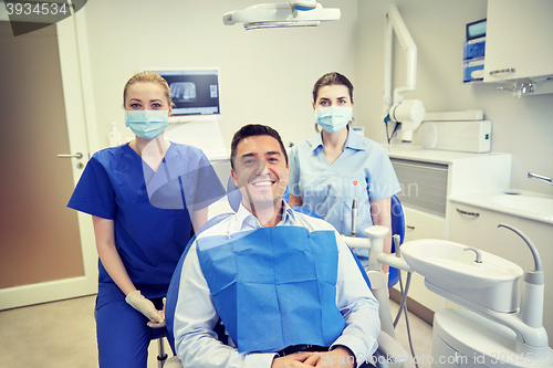 Image of happy female dentists with man patient at clinic