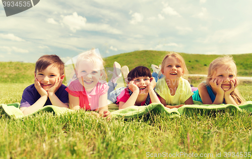 Image of group of kids lying on blanket or cover outdoors