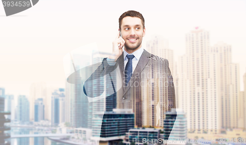 Image of young smiling businessman calling on smartphone