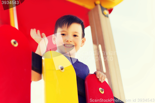 Image of happy little boy climbing on children playground