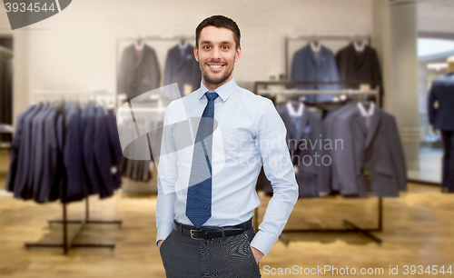 Image of happy young businessman over clothing store