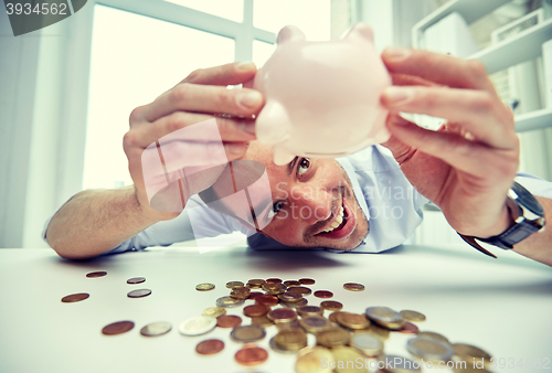 Image of businessman with piggy bank and coins at office