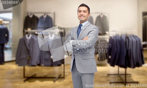 Image of happy businessman in suit over clothing store