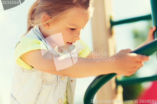 Image of happy little girl climbing on children playground