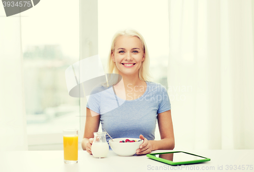 Image of smiling woman with tablet pc eating breakfast 
