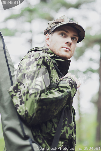 Image of young soldier or hunter with gun in forest