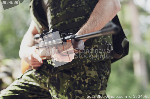 Image of close up of soldier or hunter with gun in forest