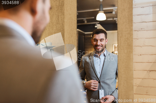 Image of man trying jacket on at mirror in clothing store