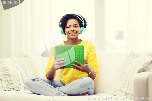 Image of happy african woman with tablet pc and headphones