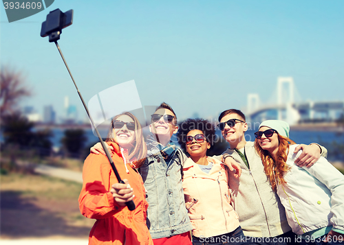 Image of smiling friends taking selfie with smartphone