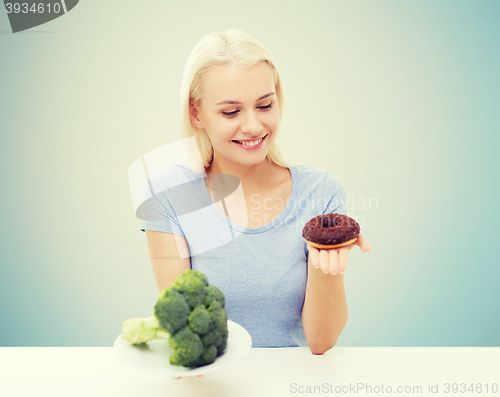 Image of smiling woman choosing between broccoli and donut