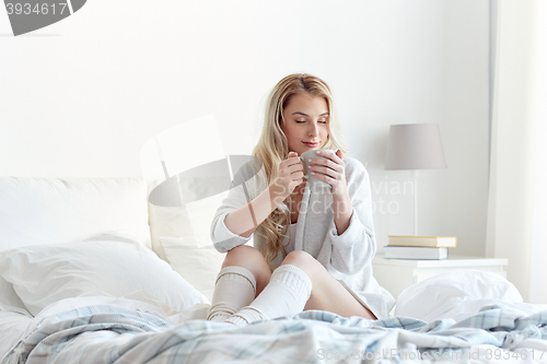 Image of happy woman with cup of coffee in bed at home