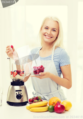 Image of smiling woman with blender preparing shake at home