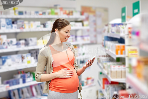 Image of happy pregnant woman with smartphone at pharmacy