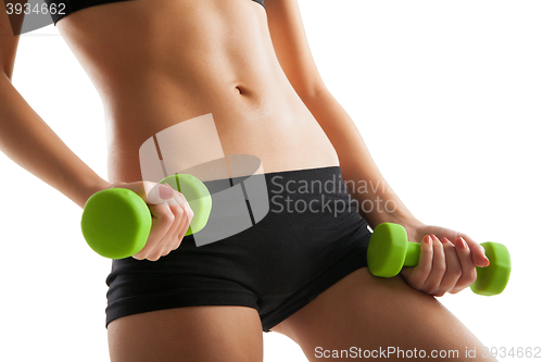 Image of Body of young fit woman lifting dumbbells