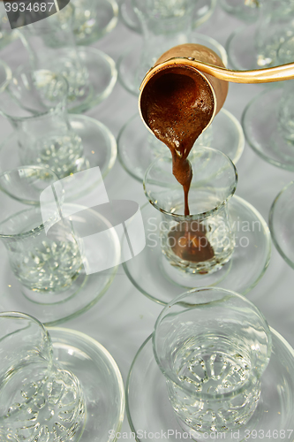 Image of Pouring turkish coffee into traditional embossed cup.