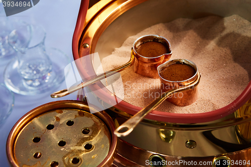 Image of Preparation of Turkish coffee in the cezve in the sand at cafe bar