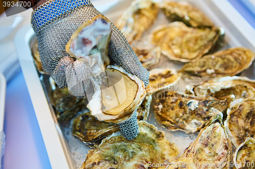 Image of Fresh oyster held open with knife in hand