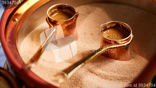Image of Preparation of Turkish coffee in the cezve in the sand at cafe bar